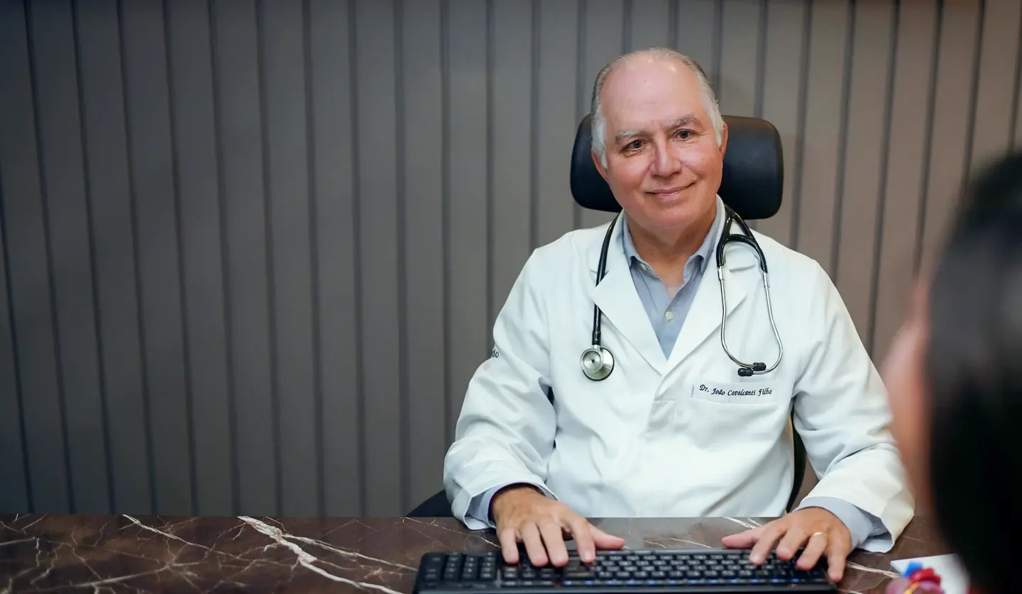 Dr. João Cavalcanti Filho, cardiologista e fundador da Ecocardio, sorri para o paciente durante a consulta